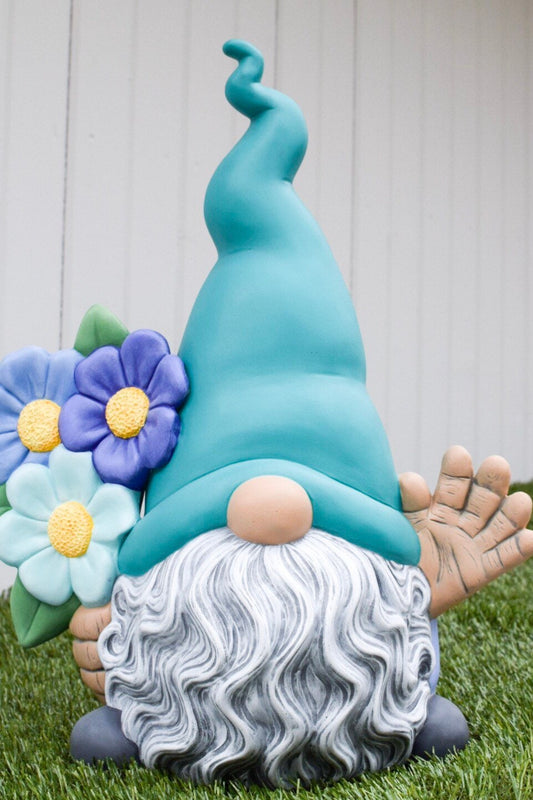 May include: A whimsical garden gnome figurine with a teal hat, gray wavy beard, and light blue flowers. The gnome's right hand is raised in a friendly wave.  The figurine is made of painted ceramic and has a charming, handcrafted look. It's a perfect decorative piece for gardens or homes.